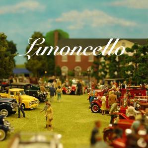 A model of what looks like a stately home, with some kind of american car display on the front lawn.