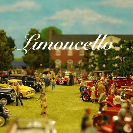 A model of what looks like a stately home, with some kind of american car display on the front lawn.